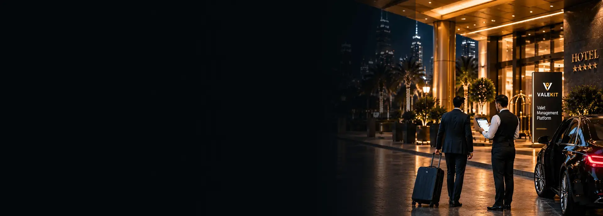 Valet attendant using ValeKit hotel valet parking software on a tablet at a hotel entrance at night